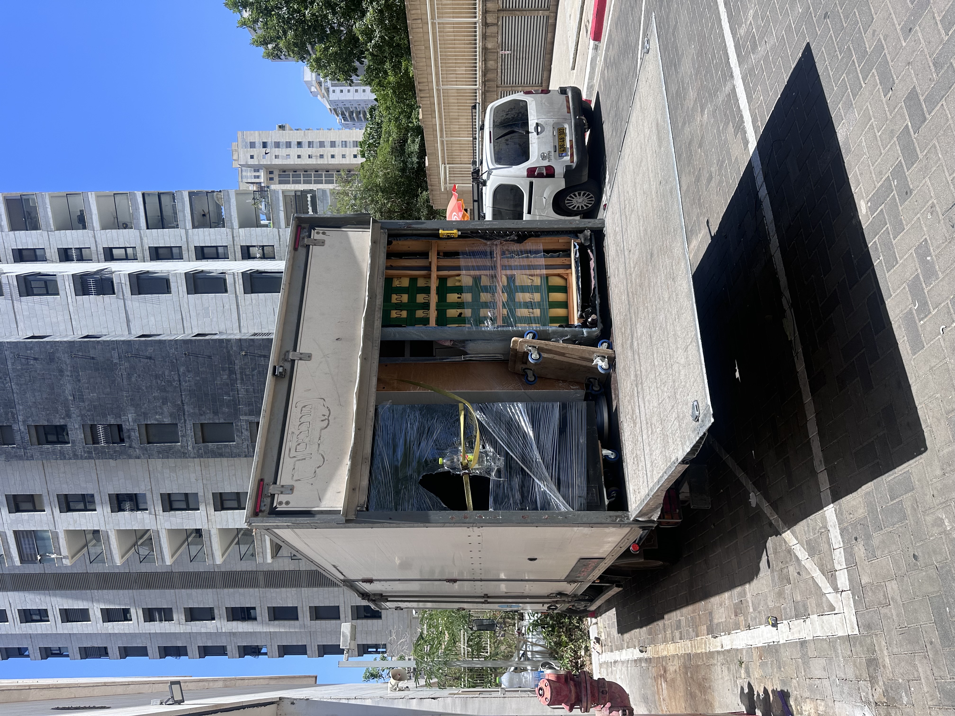 משאית פתוחה ברחוב עירוני עם רהיטים עטופים ומקובעים
